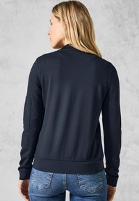 Felpa blu navy con collo rotondo, maniche lunghe e tasca laterale, realizzata in tessuto morbido e aderente in vita.