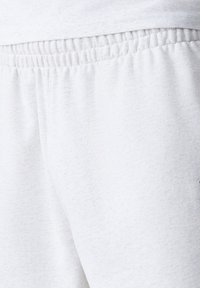Light gray cotton sweatpants with an elastic waistband, featuring a soft texture and a relaxed fit. Non-patterned with subtle color variations.