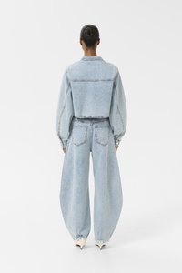 Veste en denim bleu clair au design court et aux manches bouffantes, assortie à un pantalon en denim bleu clair à jambe large et taille haute.