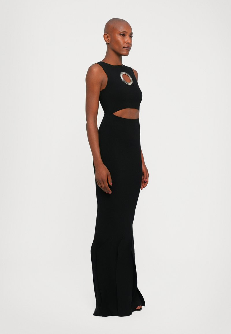 Black evening dress featuring a fitted top with cut-out sides and a circular accent, flowing into a flared hemline at the bottom.