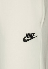 White sweatshirt with a soft texture and a black Nike logo embroidered on the left chest area, featuring a classic swoosh design.