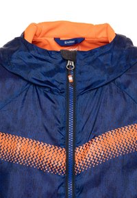 Sininen hupullinen takki oransseilla yksityiskohdilla ja verkkomaisella vuorella. Varustettu vetoketjulla ja rintakehän alueella olevan graafisen kuvion, jossa on pisteitä.