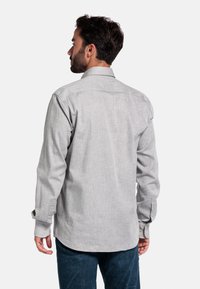 Lichtgrijze geweven shirt met lange mouwen, knoopmanchetten en een klassieke kraag. Opvallende textuur met subtiele patroon details.