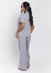 Conjunto de loungewear gris hecho de una tela suave, que incluye una camiseta de manga corta y pantalones de pierna ancha con detalles de contraste en los bordes.