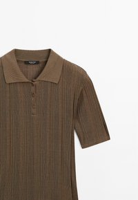Polo en maille marron avec un col rabattu, une patte de boutonnage à trois boutons et des manches courtes. Tissu texturé avec des rayures verticales.