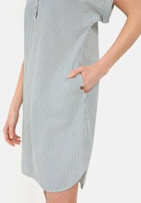 Gestreiftes Baumwollkleid mit kurzen Ärmeln, seitlichen Taschen, einer lockeren Passform und einem abgerundeten Saum. Es hat blau-weiße senkrechte Streifen.
