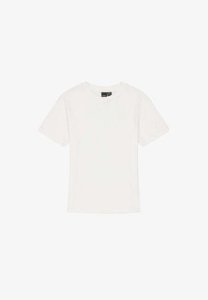 Adolescent portant un T-shirt blanc à manches courtes, un short kaki vert jusqu'au genou, et des baskets noir et blanc, debout devant un fond blanc.