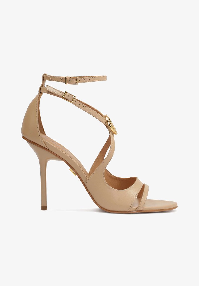 Nude spalvų aukštakulniai sandalai su keliais dirželiais ir kulkšnies sagtimi. Lygus odos paviršius, minimalistiškas dizainas ir smailus kojų pirštas.