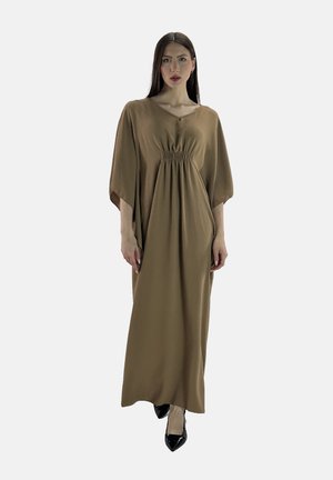 Langes braunes Kleid aus strukturiertem Material mit V-Ausschnitt, elastischem Gummi an der Taille und Glockenärmeln. Trägt schwarze spitze Schuhe.