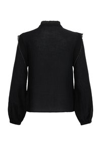 Blouse noire à manches longues avec col montant à volants et manches légèrement bouffantes, en tissu subtilement texturé avec des détails délicats de coutures.