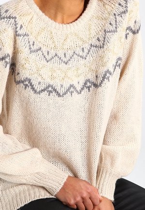 Cremfarbener Strickpullover mit rundem Halsausschnitt, der ein geometrisches Muster in Grau und Gelb über den Schulterbereich aufweist und lockere Ärmel hat.