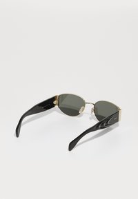 Ochelari de soare cu lentile ovale de culoare verde închis, brațe din plastic negru și accente din metal aurit. Prezintă detalii curbate pe brațe cu gravuri.