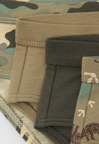 Quatre paires de boxers à motifs en vert, beige et gris foncé avec des ceintures élastiquées et des coutures à plat.