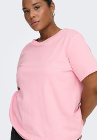 Lyserød bomulds-T-shirt med rund halsudskæring og korte ærmer. Har en afslappet pasform og blød tekstur. Ingen mønster eller dekorationer.