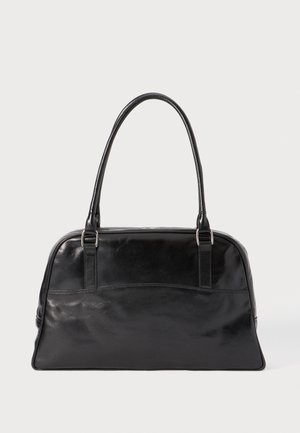 Sac à main en cuir noir brillant avec deux longues anses et un panneau avant lisse et légèrement courbé sur fond blanc uni.