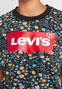 Mustapohjaista kukkakuosisia lyhythihaista paitaa, jossa on näkyvästi punainen Levi's-logo rinnan kohdalla.