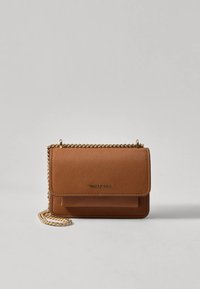 Hnědá taška přes rameno z broušené kůže se zlatým řetízkovým popruhem a magnetickým uzávěrem na klopě. Obsahuje přední kapsu a ražené logo.