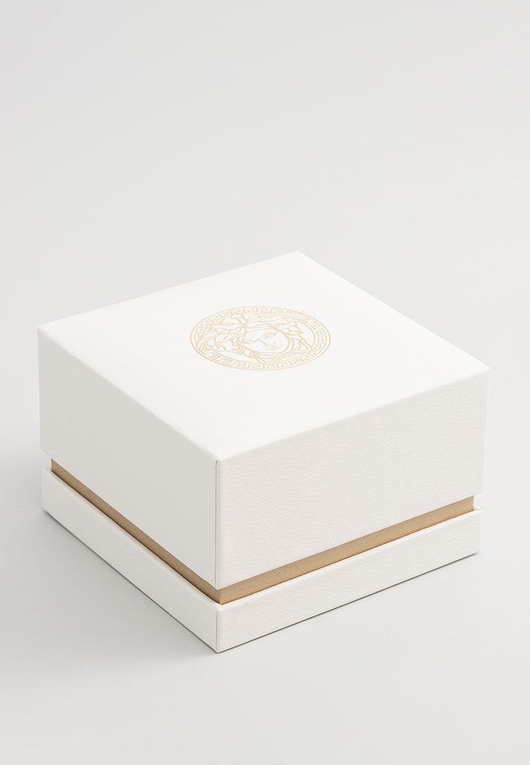 Boîte carrée blanche avec une surface texturée, présentant un motif doré en relief sur le dessus et une bande dorée décorative autour de la base.