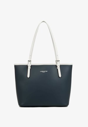 Sac cabas Lancaster Paris bleu marine avec anses et bordures blanches, forme rectangulaire, et détails de boucles argentées sur les poignées.