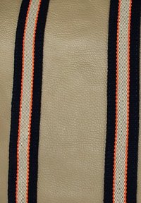 Surface en simili cuir tan avec trois rayures verticales : marine, beige et orange. La texture du tissu est lisse avec des détails tissés contrastés.