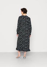 Vestido preto com bolinhas azul claro, mangas longas e bainha com babados. Fecho nas costas em forma de chave e tecido macio e fluido. Saltos azul claro.