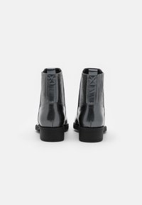 Stivaletti neri alla caviglia con finitura lucida, caratterizzati da una texture rigata sui lati, punta arrotondata e piccoli tacchi a blocco.