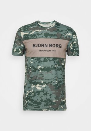 Krótki rękaw, moro koszulka z zielonym i beżowym pikselowym wzorem, z napisem "BJÖRN BORG STOCKHOLM 1956" na piersi.