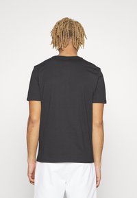 Camiseta negra de manga corta con cuello redondo. Hecha de una tela suave, con un diseño simple y un corte relajado.
