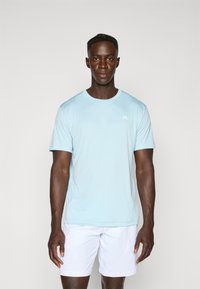 Light blue short-sleeve athletic t-shirt made from breathable material, featuring a round neckline and a small white logo on the left chest.