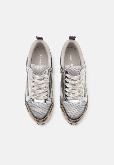 Sneaker in rete argento e grigio con punta tonda, sovrapposizioni testurizzate e lacci piatti. Presenta un manico sul tallone e una soletta imbottita.