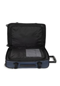 Blauwe koffer met een harde schaal en uitschuifbaar handvat, opengeklapt om een zwarte binnenkant met een vlakke zak en een gladde voering te tonen.