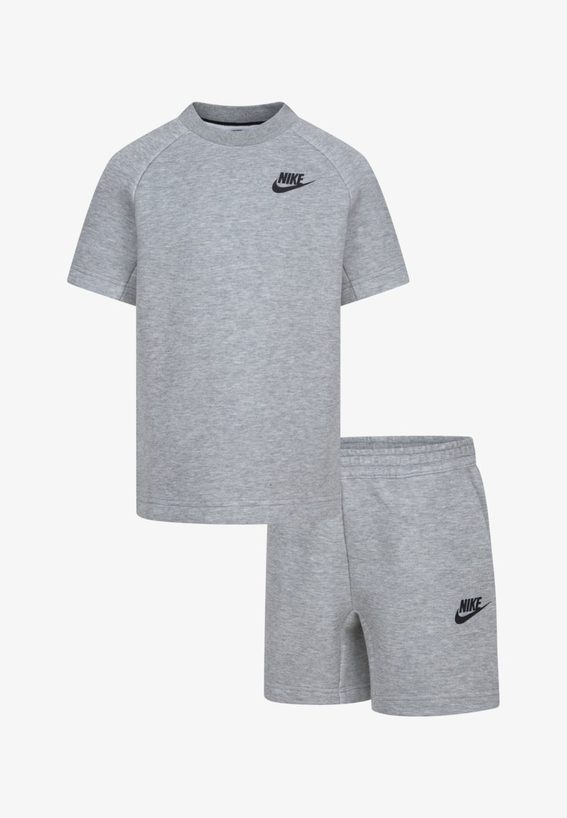 Pilkas medvilnės ir elastano sportinis rinkinys, kuriame yra trumpomis rankovėmis marškinėliai ir derančios šortai. Abu turi juodą Nike logotipą priekį.