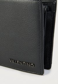 Čierna kožená peňaženka s textúrou zrna, vybavená jemne vyrazeným logom. Kompaktný dizajn s viacerými priehradkami na karty a elegantným skladacím prevedením.