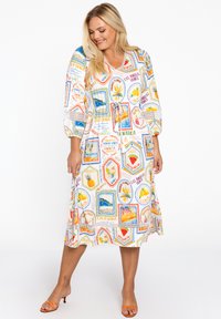 Kleid mit kurzen Ärmeln und V-Ausschnitt, versehen mit einem bunten Druck von Postkarten und Früchten. Hergestellt aus leichtem Stoff mit einem Kordelzug in der Taille.