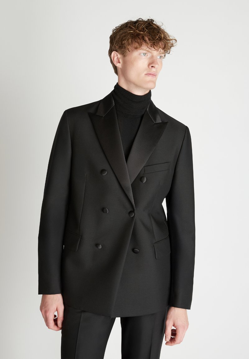 Dubbelbreasted zwarte blazer van soepel materiaal, met satijnen revers, twee voorzakken en een slim fit, gecombineerd met een coltrui.