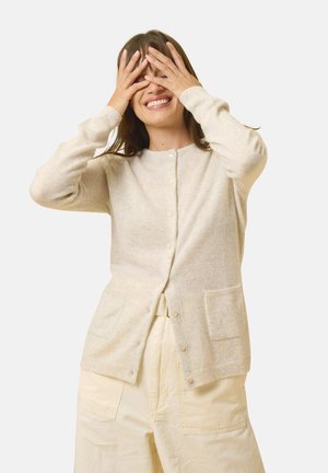 Hellbeige Cardigan aus weicher Wolle. Verfügt über einen runden Halsausschnitt, lange Ärmel, eine Knopfleiste vorne und zwei aufgesetzte Taschen. Glatte Textur.