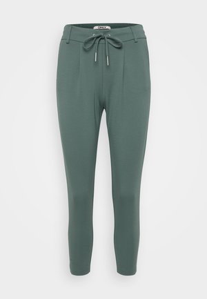 Pantalon vert ajusté en matériau doux et extensible. Doté d'une taille à cordon, de plis et de jambes fuselées. Design simple et minimaliste.