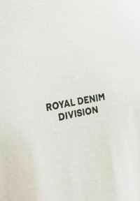 Weißes Baumwoll-T-Shirt mit dem Aufdruck "ROYAL DENIM DIVISION" in kräftigen schwarzen Buchstaben. Weiche Textur mit klassischem Rundhalsausschnitt.