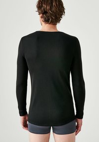 Zwarte geribbelde langemouwen shirt met een ronde hals en een subtiele textuur, van achteren getoond met een aansluitend ontwerp.