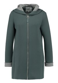 Lange groene zip-up jas met capuchon, voorzien van grijze voering in de capuchon en manchetten, voorzakken en een ronde ritssluiting trekband.