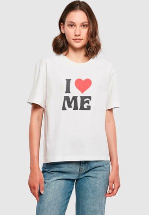 Bela bombažna majica s kratkimi rokavi z grafiko "I ❤️ ME" v črni in rdeči barvi. Ohlapen kroj, preprost dizajn in gladka tekstura.