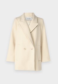 Blazer crema doppiopetto con risvolti, due tasche frontali e una sottile texture. Presenta bottoni chiari per la chiusura.