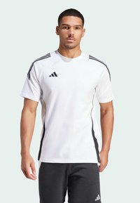 Camiseta atlética corta de mangas blancas con rayas negras en los hombros y los lados, con un logo de Adidas en el pecho.