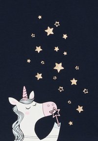 Marineblaue T-Shirt mit einem weißen Einhorn mit pinkem Horn, das einen pinken Sternenstab hält, umgeben von goldenen Glitzersternen.