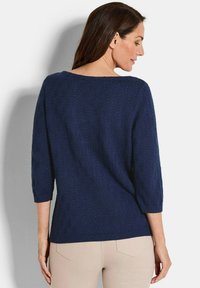 Marineblauer Strickpullover mit Dreiviertelärmeln, der ein strukturiertes Muster und einen gerippten Saum am Ausschnitt und am unteren Ende aufweist.