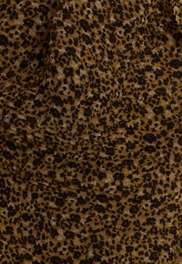 Tejido de estampado de leopardo que presenta un patrón marrón y negro, con una superficie texturizada y acentos brillantes. Drapado con detalles fruncidos.