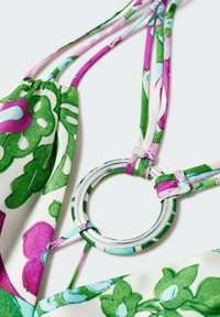 Tissu à imprimé floral avec des couleurs roses et vertes, comprenant un anneau argenté circulaire et plusieurs sangles de couleurs variées. Texture lisse.