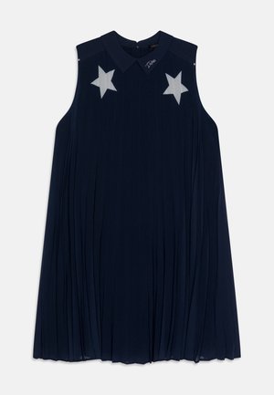 Robe sans manches bleu marine avec un design plissé, présentant deux appliqués en forme d'étoile blanche sur la poitrine et un col.