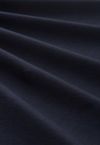 Tissu din bumbac de culoare bleu închis cu o textură netedă, afişând plieguri curbate și o suprafață uniformă. Nu sunt prezente modele sau accente notabile.