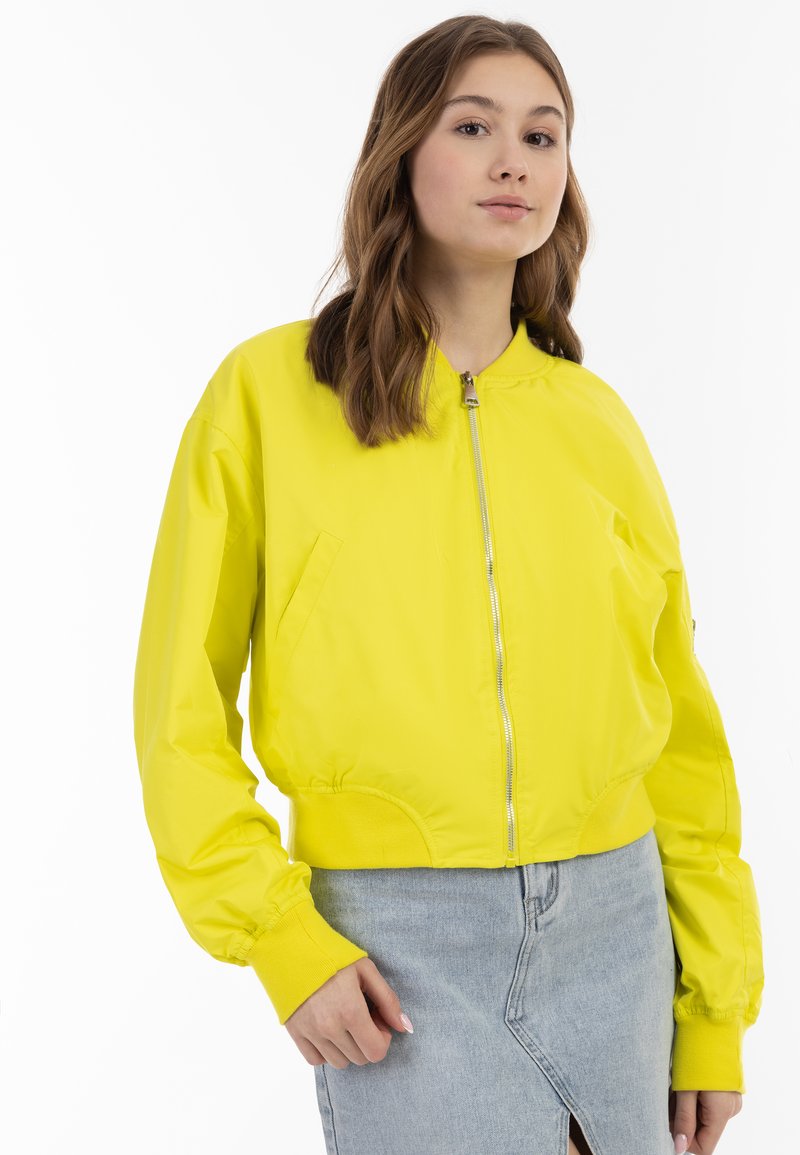 Giacca bomber gialla con zip frontale, polsini e orlo a costine. Tessuto liscio, design corto e tasche laterali.